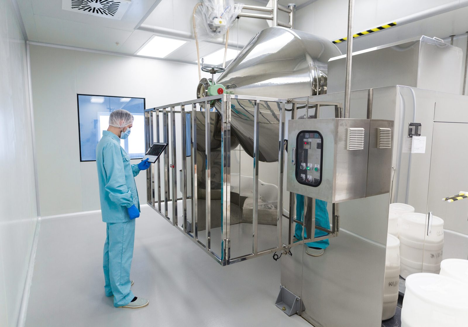 Man standing in blue uniform looking at machine.
