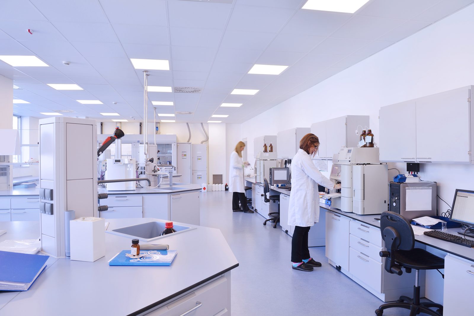 caucasian scientist in blue lab suit and gloves stand on platform and look in the chromed tank, clean laboratory, tank on front